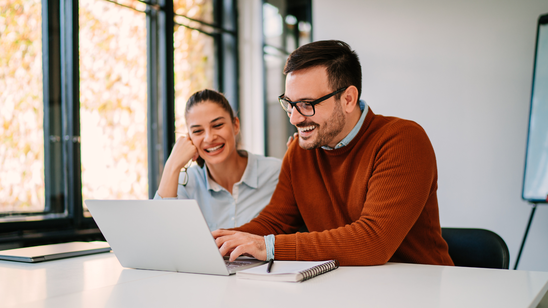 Two business colleagues reviewing HR vendor options together on a laptop