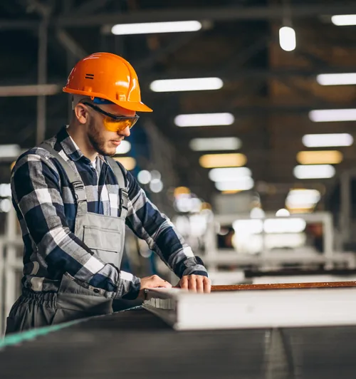 Worker in a hard hat operating equipment on a manufacturing floor