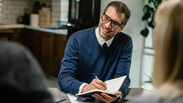 Smiling advisor taking notes during a consultation with clients